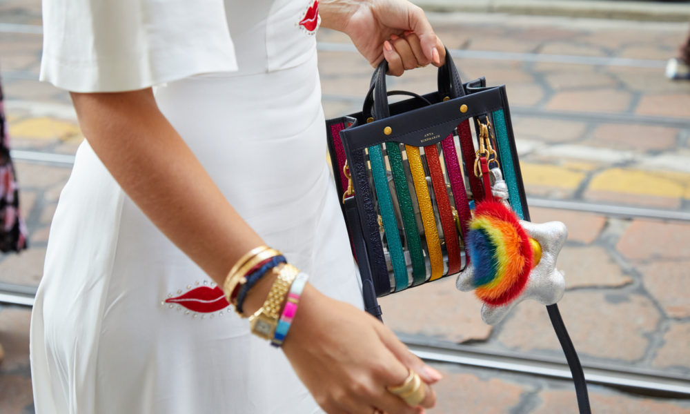 MILAN, ITALY - SEPTEMBER 20, 2018: Woman with Anya Hindmarch colorful bag and golden Cartier watch before Vivetta fashion show, Milan Fashion Week street style